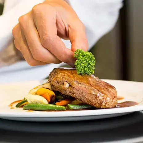 NorthRidge Chef Created Meals, chef garnishing a plate.